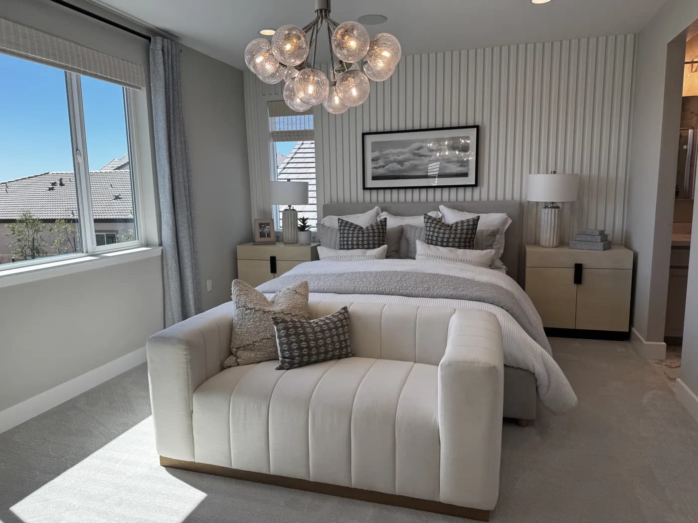 Primary suite at Amoruso Ranch featuring a chandelier, channeled bench, and reeded accent wall